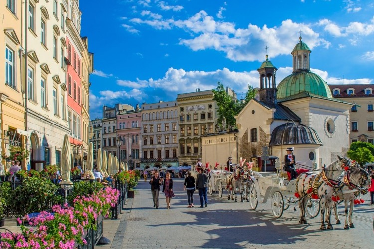 Mały Rynek w Krakowie z dorożką wraz z dwoma koniami i turystami spacerującymi po brukowanej ulicy