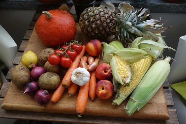 Owoce i warzywa na tacy: marchewki, pomidory, kukurydza, brzoskwinie, dynia, ananas, cytryna, cebule czerwone, czosnek 